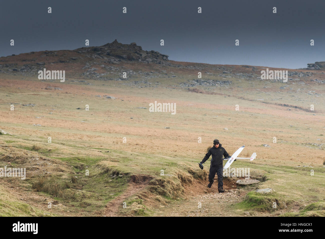 A man carries a model glider on Rough Tor, designated as an area of Outstanding Natural Beauty on Bodmin Moor in Cornwall. Stock Photo