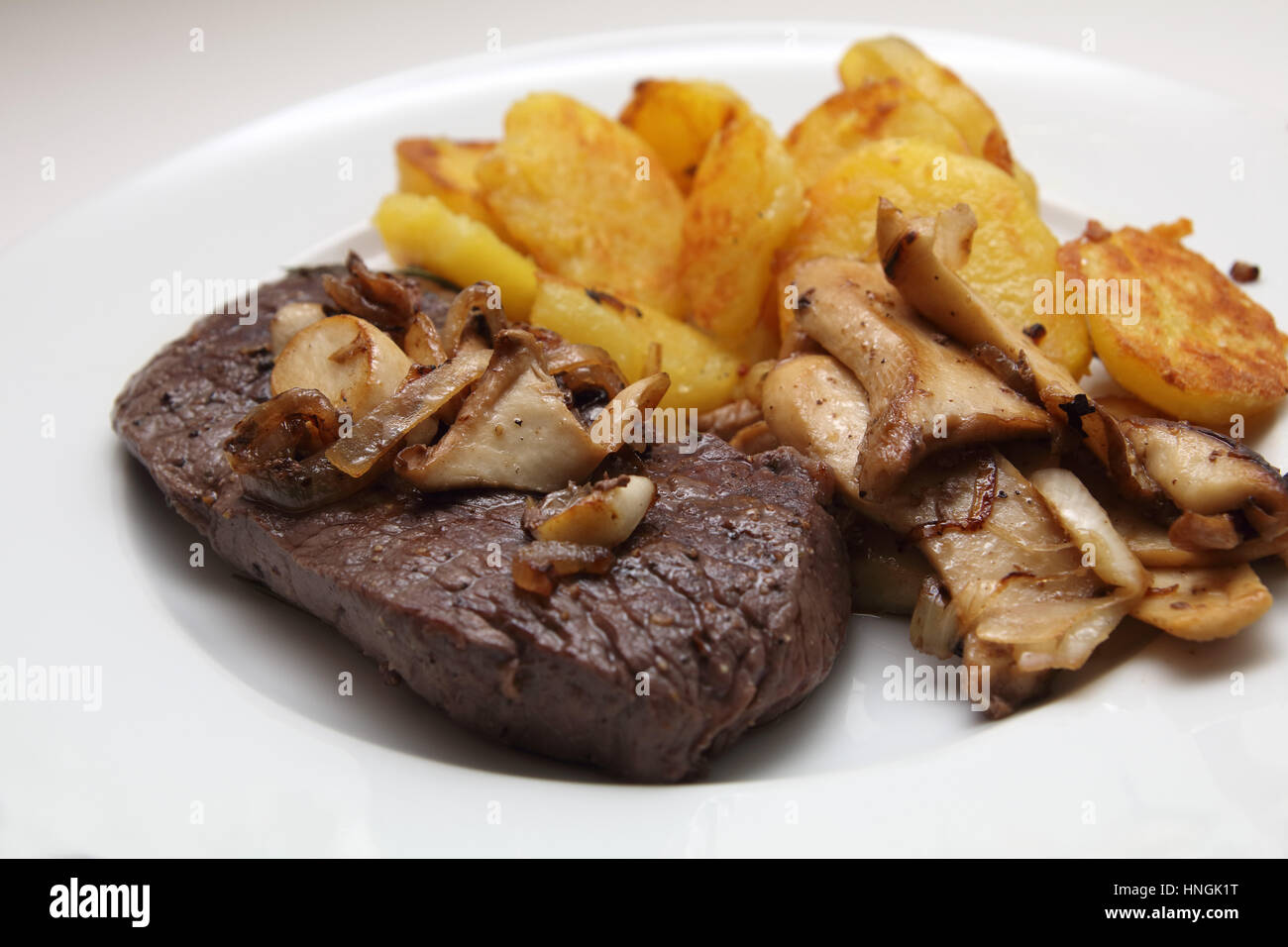 Steak mit Bratkartoffeln und Kräuterseitlinge Stock Photo