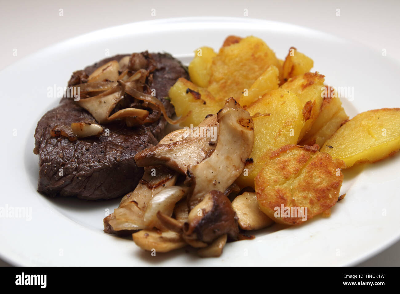 Steak mit Bratkartoffeln und Kräuterseitlinge Stock Photo