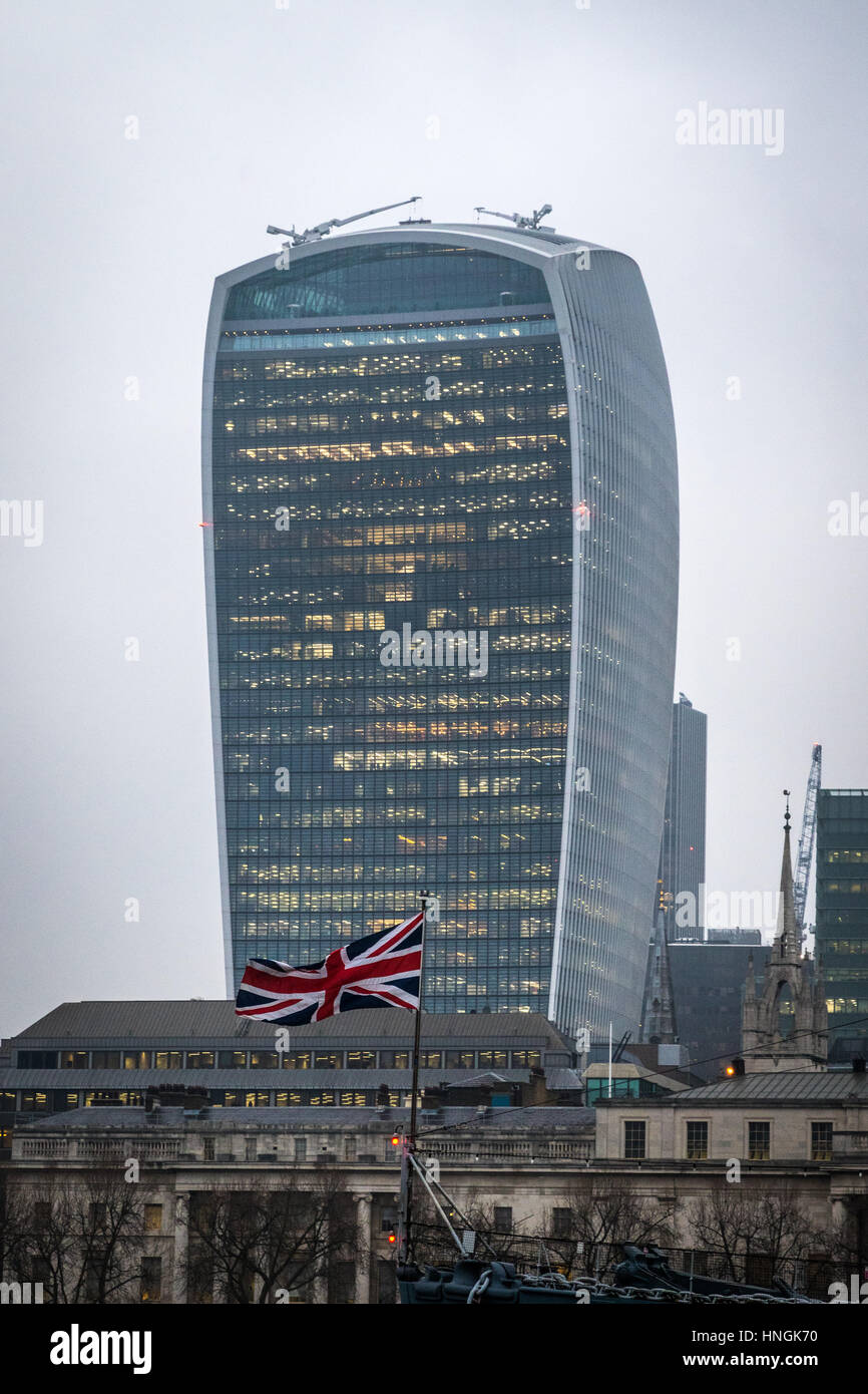 The union jack on HMS Belfast flies in front of 20 Fenchurch Street, the building known as the Walkie Talkie, in the City of London Stock Photo