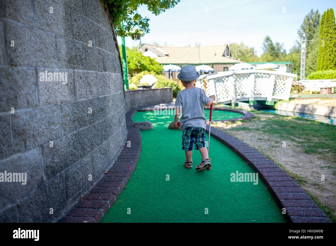 Little boy preschooler playing mini-golf or crazy golf at a mini-golf course in summer Stock Photo