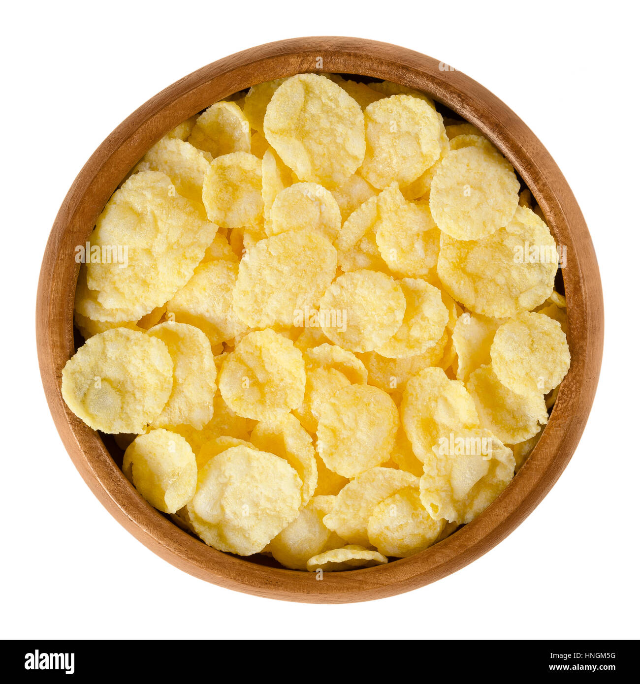 Corn flakes in wooden bowl. Crispy cornflakes, a popular breakfast cereal made by toasting small flakes of corn. Stock Photo