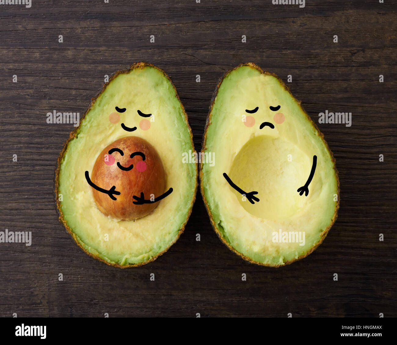An avocado parent and child in embrace beside another avocado who is sad that is it without a child or baby Stock Photo