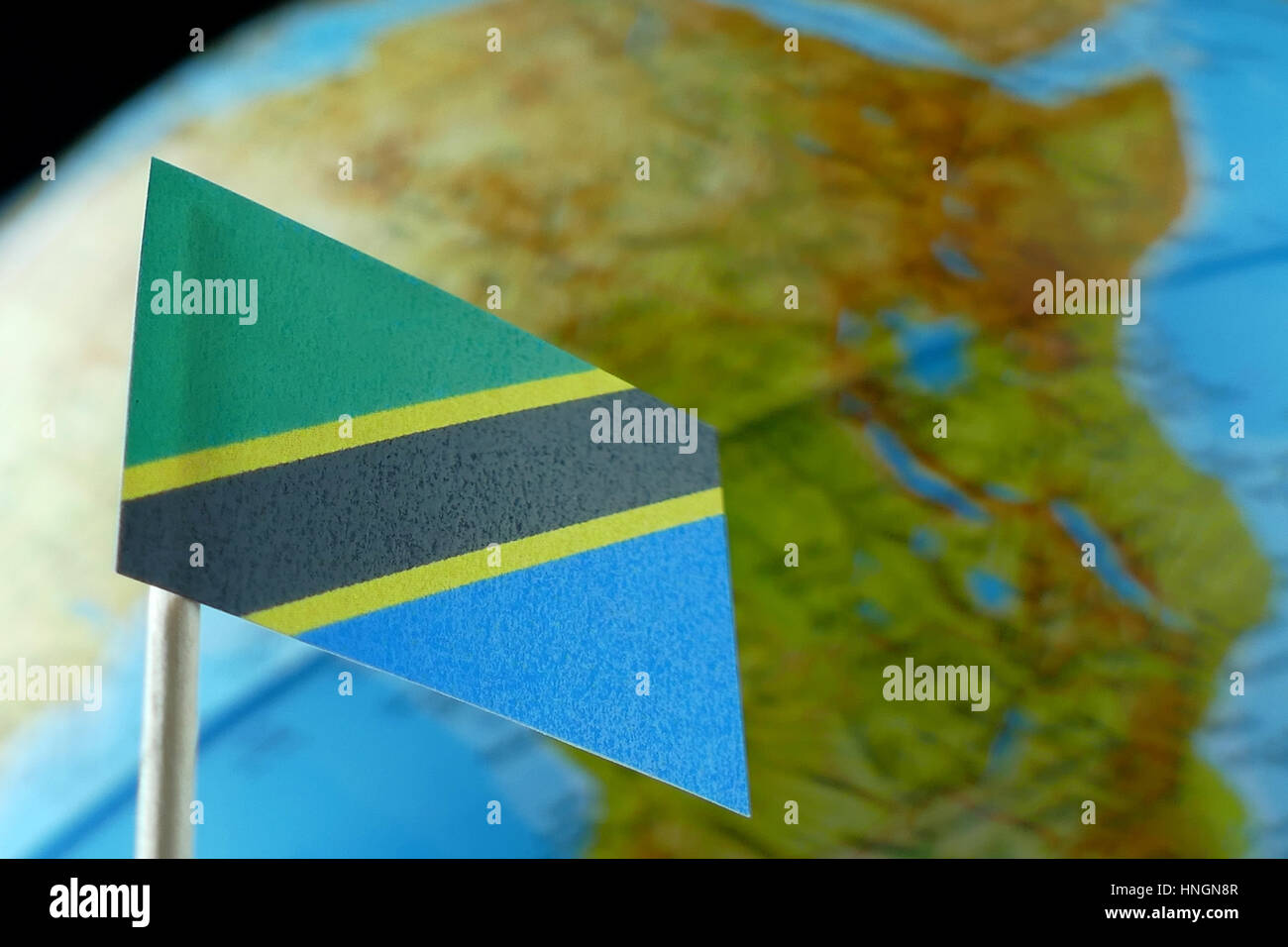 Tanzania flag with a globe map as a background macro Stock Photo - Alamy