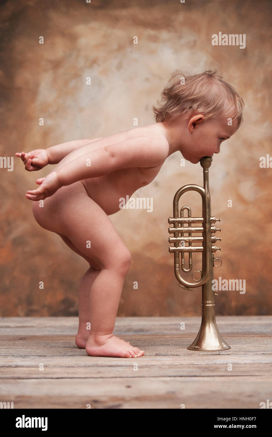 Three year-old girl, naked, blowing in a trumpet, Austria Stock Photo