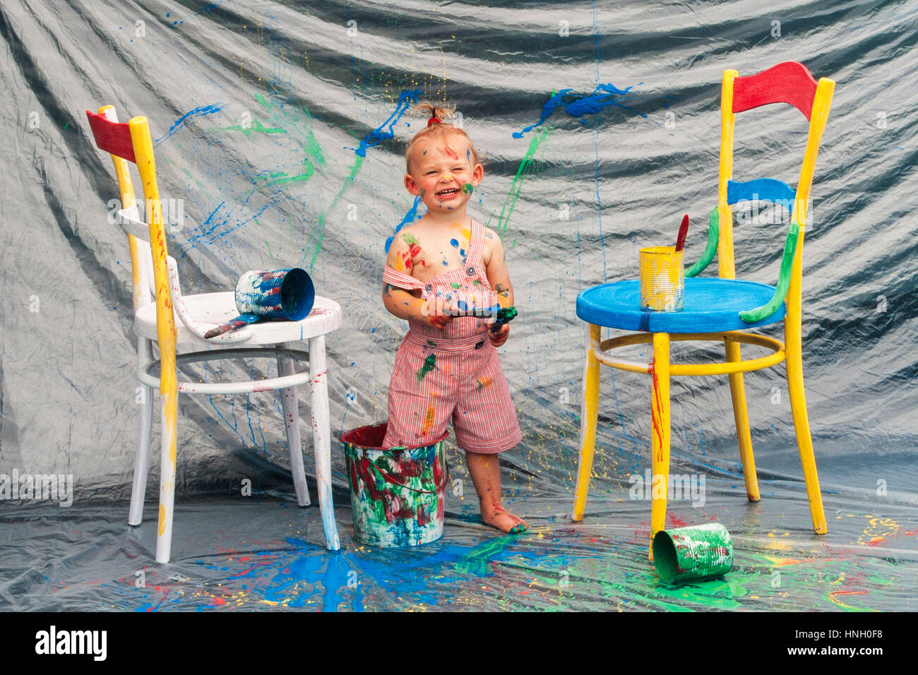 Four year-old girl standing with feet in paint pot, Austria Stock Photo