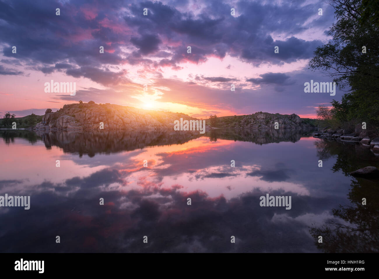 River against colorful sky with clouds and rocks at sunset in summer. Beautiful landscape with lake, mountains, sunlight and blue cloudy sky reflected Stock Photo
