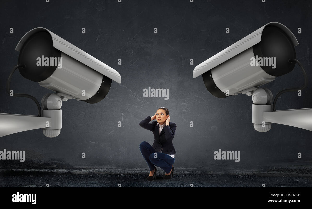 Unrecognizable businesswoman in room standing under security camera