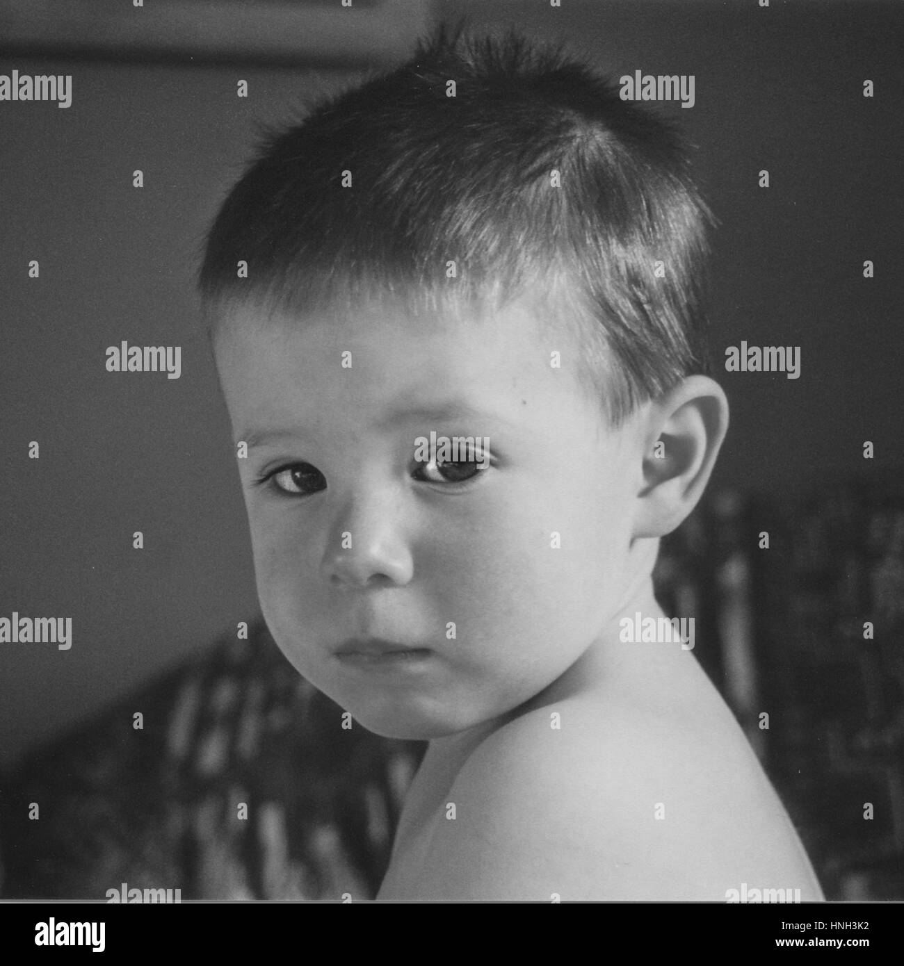 Head and shoulder shot of toddler looking sad anxious downcast forlorn lonely in black and white Stock Photo