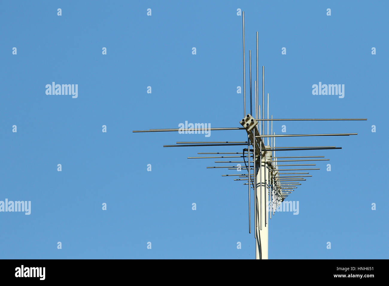 Modern crossed communications antenna stack on metal pole against blue skies with space for copy Stock Photo