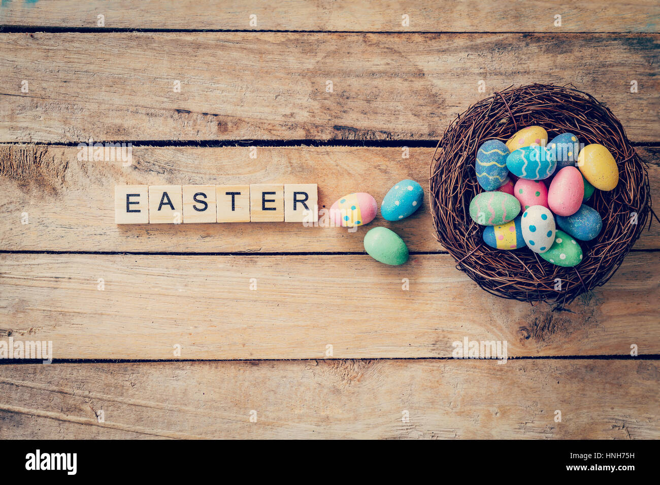 Colorful easter egg in the nest and wood text for Easter on wood background with space Stock Photo
