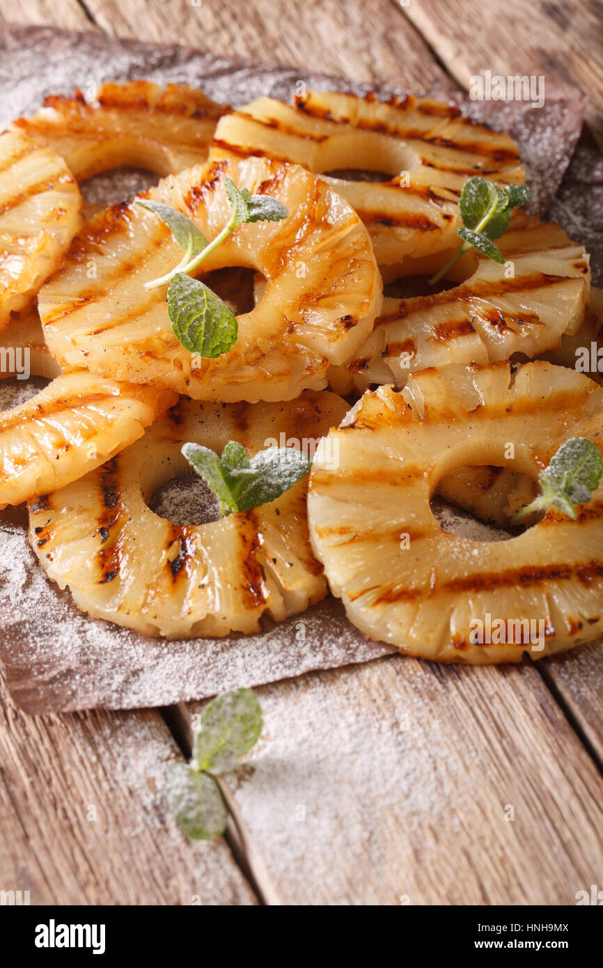 Grilled Pineapple with mint and powdered sugar close-up on the table. vertical Stock Photo