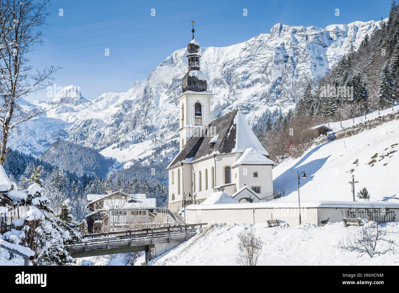 Classic view of famous Parish Church of St. Sebastian embedded in scenic winter wonderland landscape in the Alps, village of Ramsau, Bavaria, Germany Stock Photo