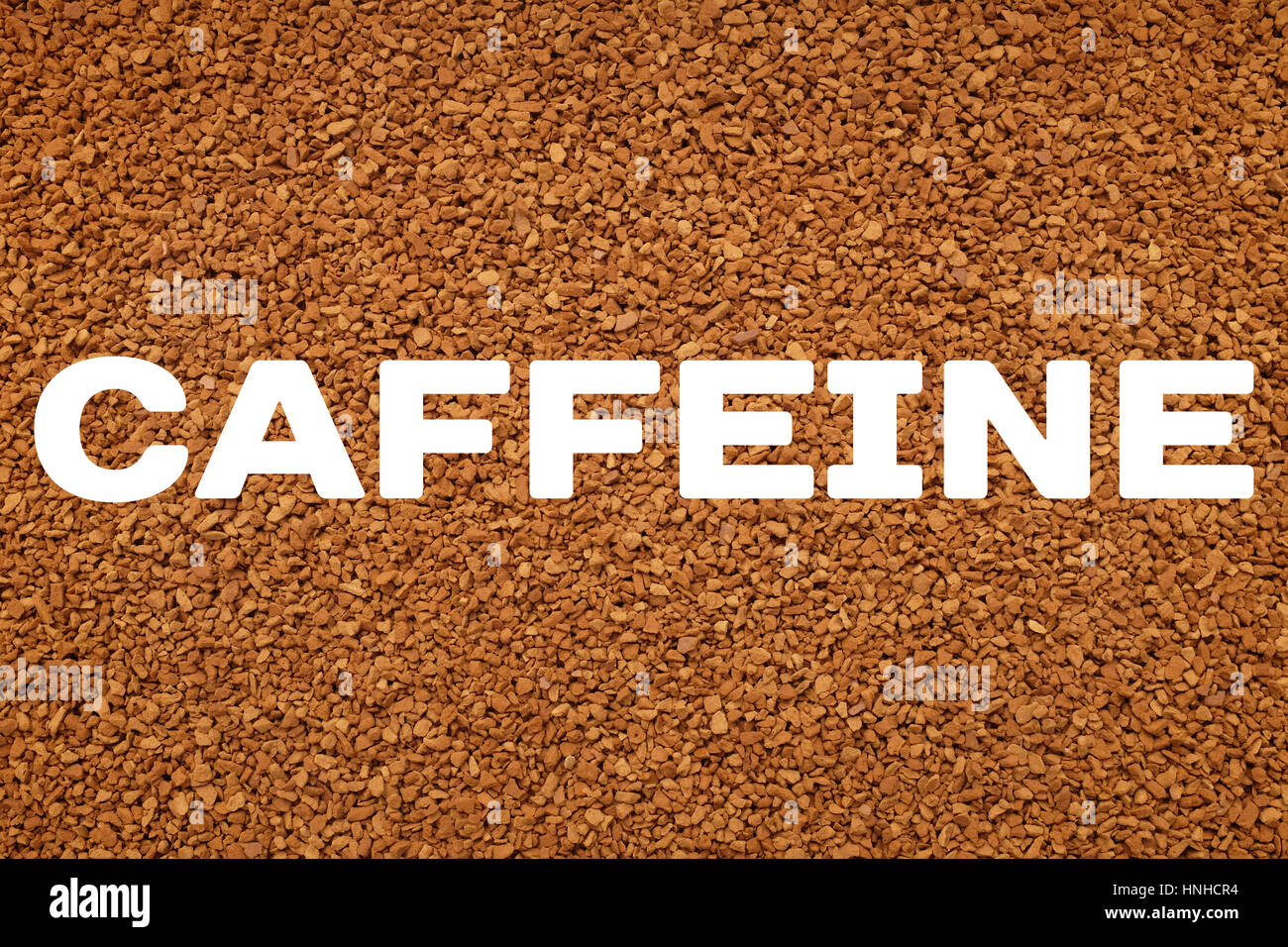 CAFFEINE text written over background of instant coffee granules Stock