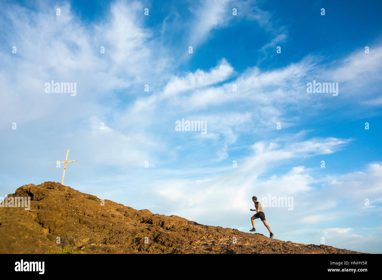 Trail runner running uphill on mountain summit Stock Photo