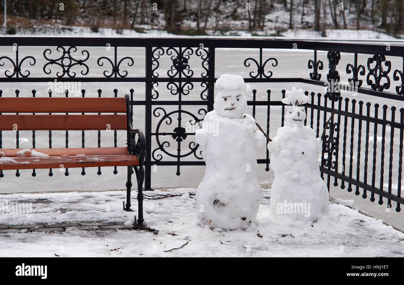 two little snowman in the Park at the lake near the benches Stock Photo