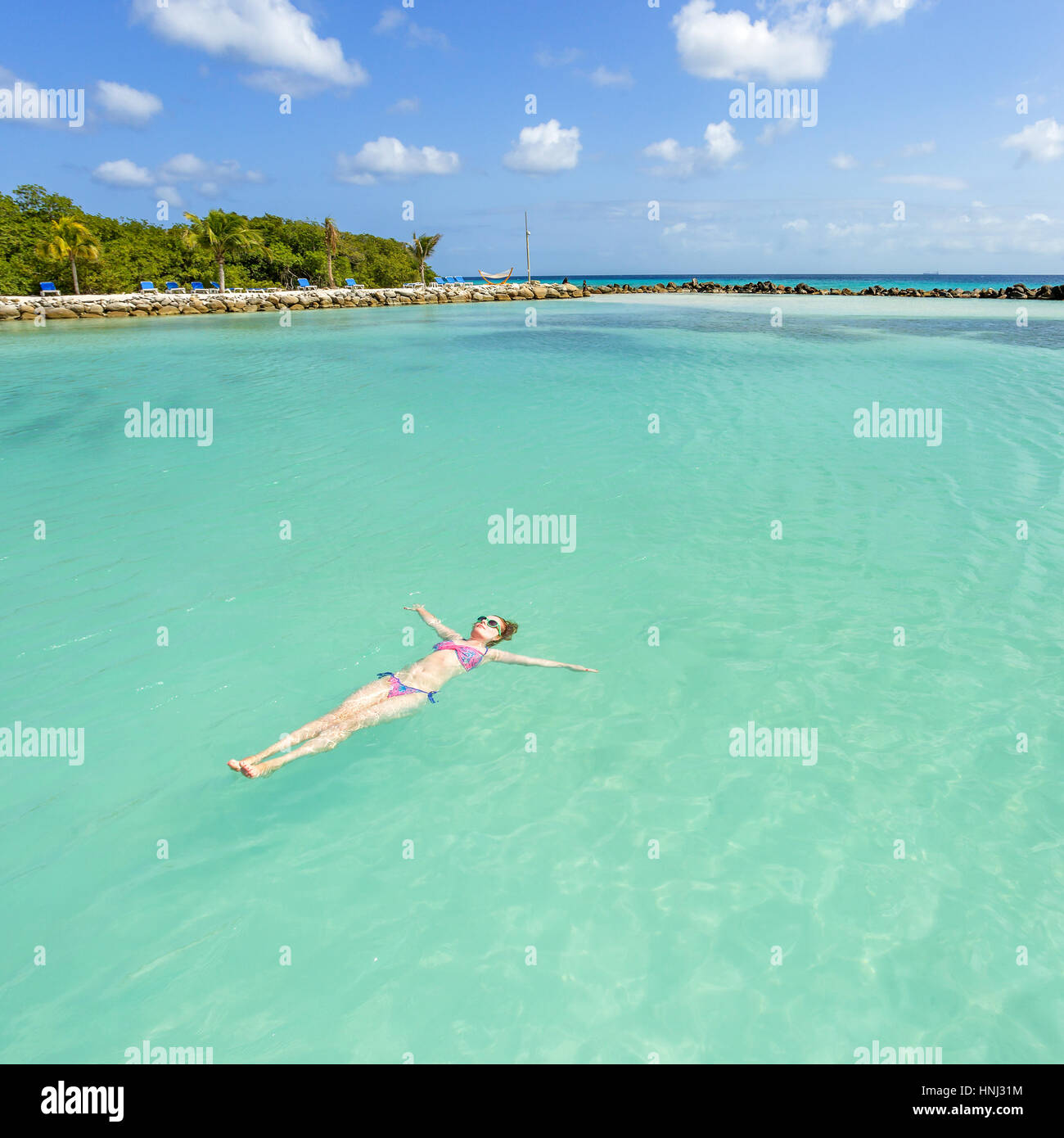 Woman floating and relaxing in turquoise waters at colorful tropical beach Stock Photo