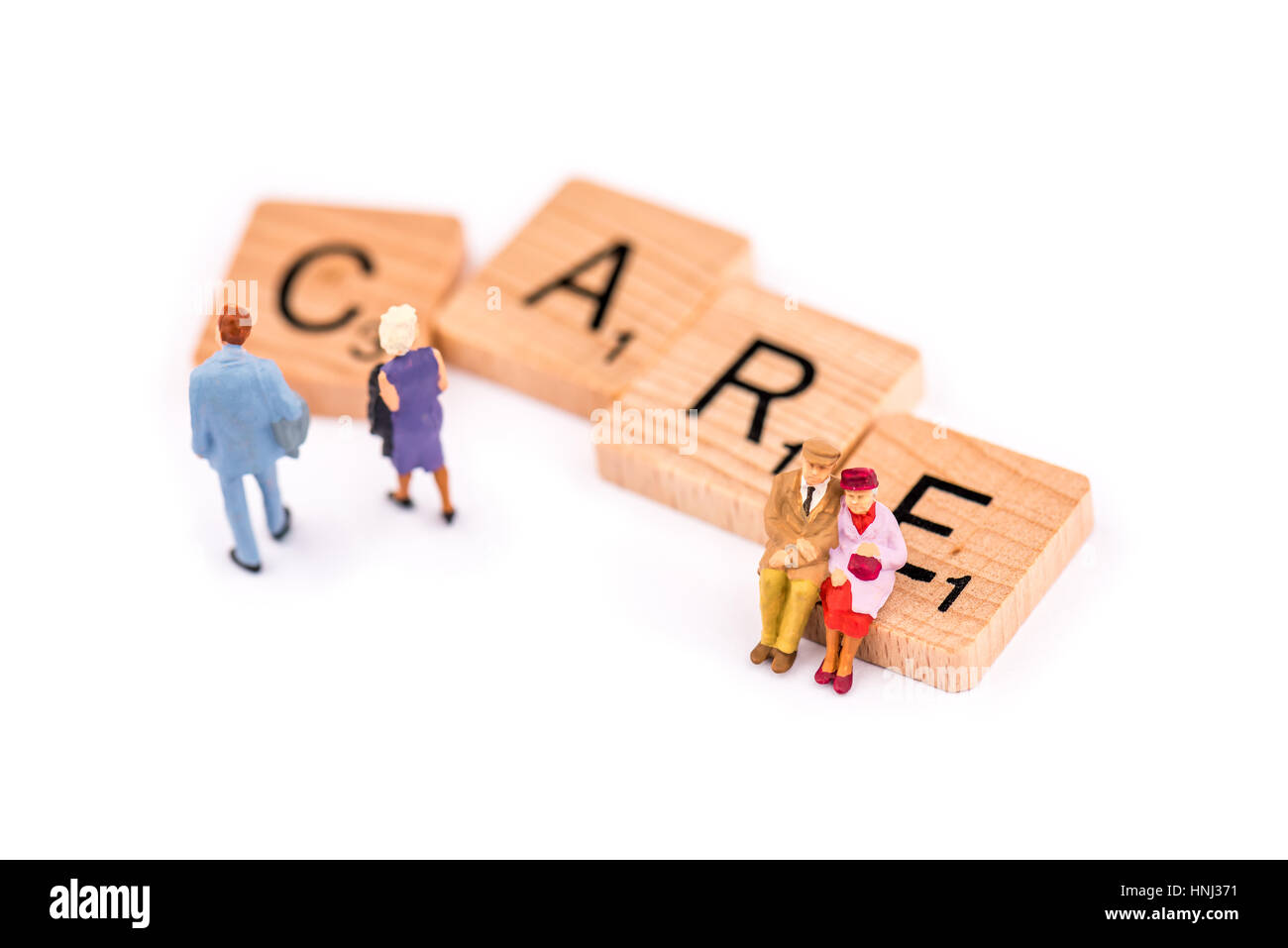 Scrabble letters make up the word CARE. An elderly couple sit on the