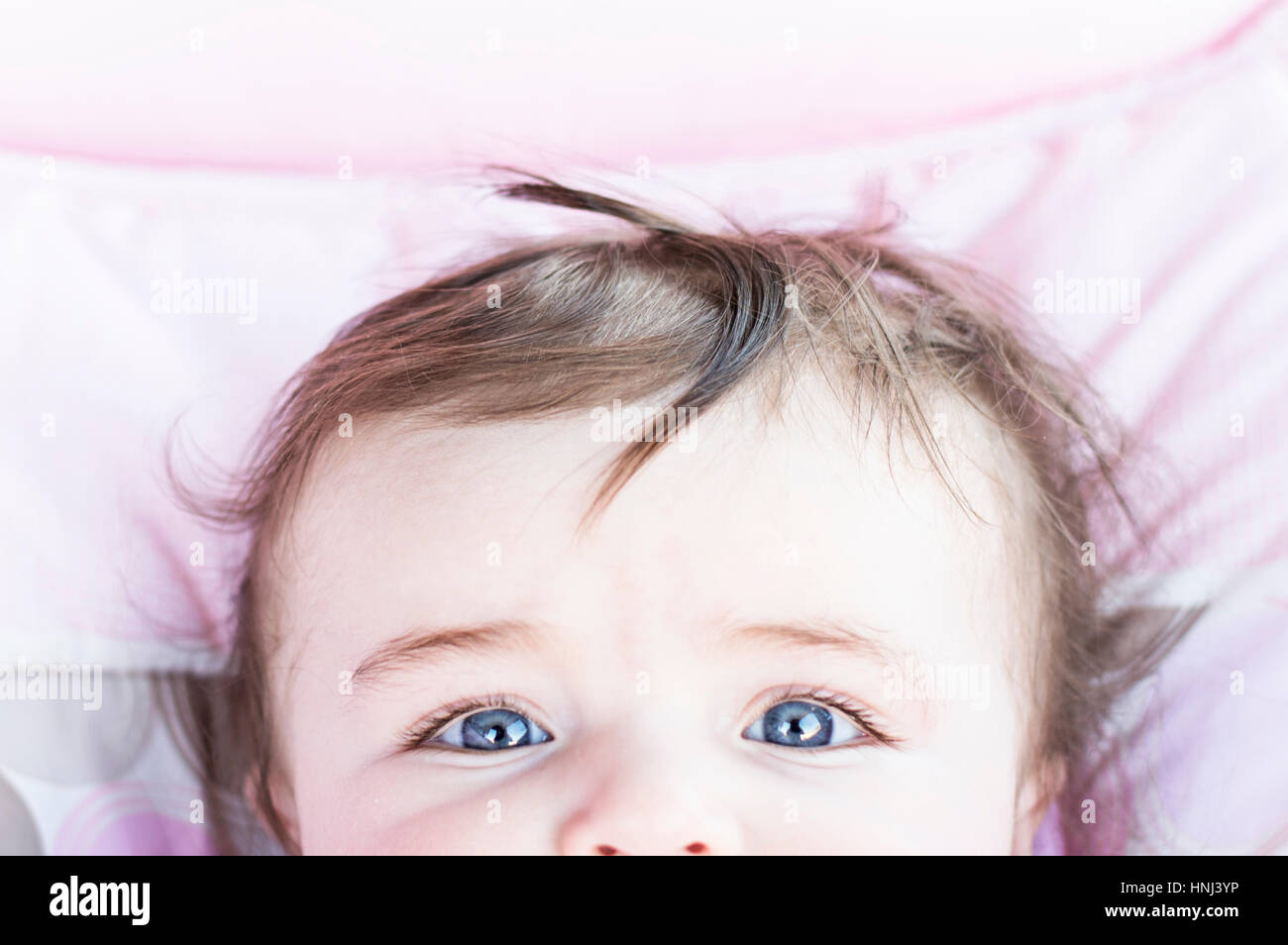 Cropped image of baby girl lying on bed Stock Photo