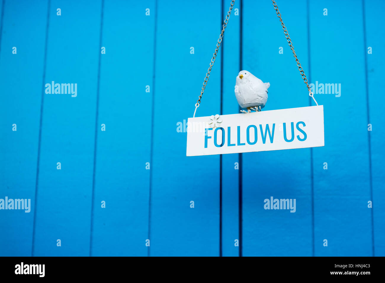 Follow Us signboard on a blue wooden background Stock Photo