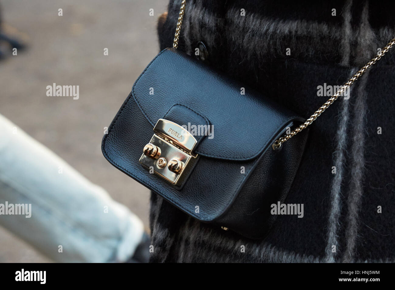 MILAN - JANUARY 14: Woman with Furla black leather bag before Diesel Black Gold fashion show, Milan Fashion Week street style on January 14, 2017 in M Stock Photo