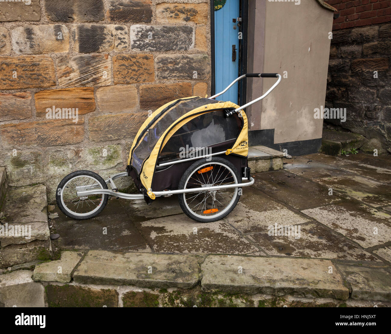 A Burley D'lite pram parked outside a quaint stone cottage in Staithes, North Yorkshire,England, UK Stock Photo