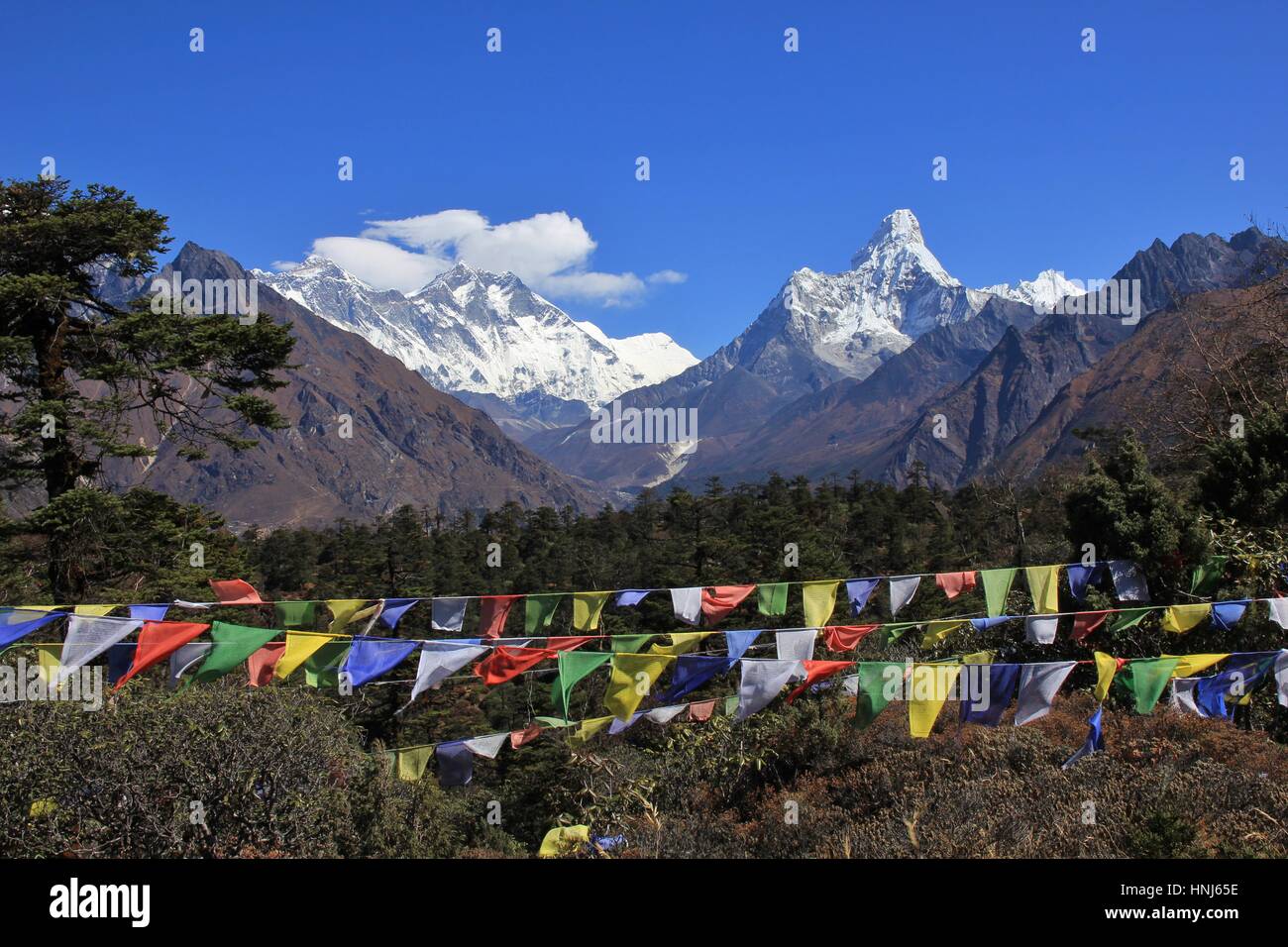 Scene near Khumjung, Everest National Park, Nepal. Prayer flags and snow capped mountains Lhotse and Ama Dablam. Stock Photo