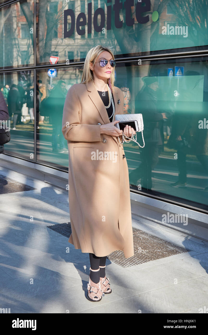 Blond woman with beige coat and velvet shoes before Giorgio Armani fashion show, Milan Fashion Week street style on January 17, 2017 Stock Photo