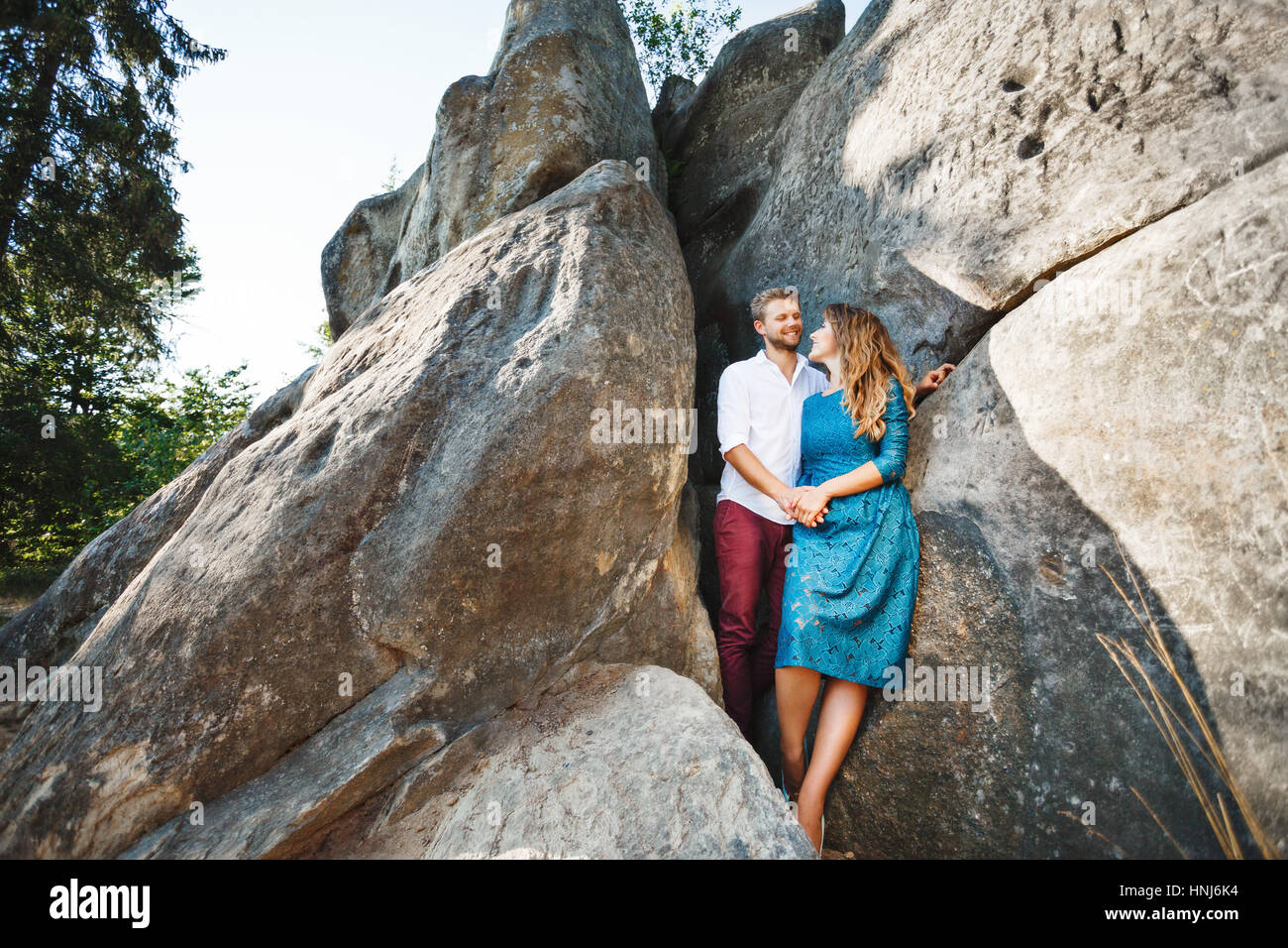 Smiling couple standing near rocks Stock Photo - Alamy