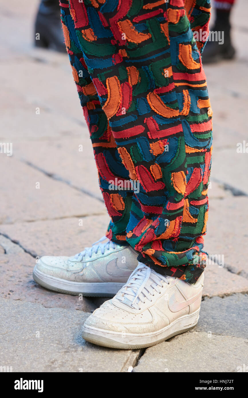 Man with white iridescent Nike shoes and colorful trousers before Salvatore Ferragamo fashion show, Milan Fashion Week street style. Stock Photo