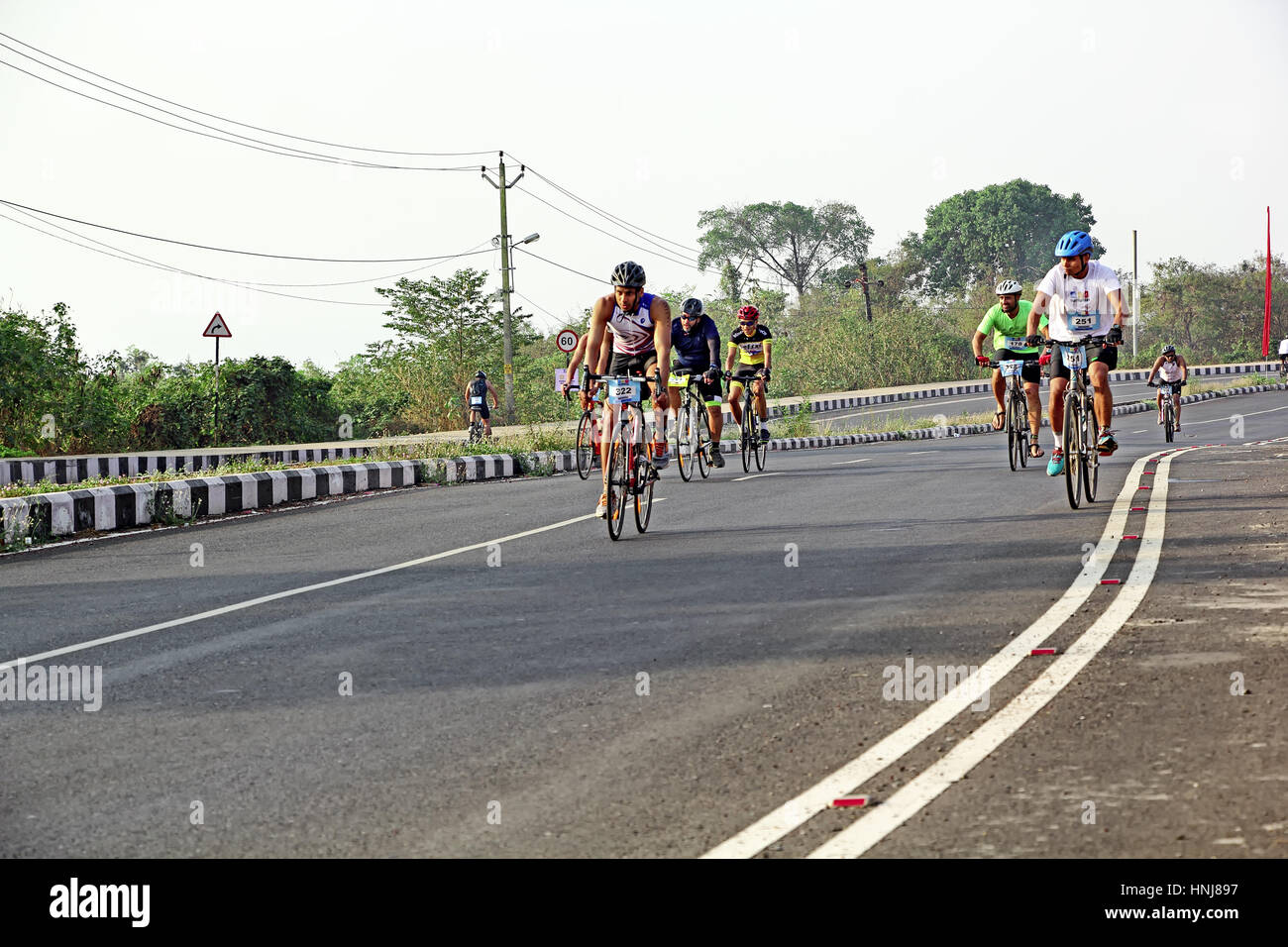 Participants in Goa Triathlon 2017, after finishing swimming part, competing in the running and cycling leg in the scenic highway at Bambolim in Goa Stock Photo