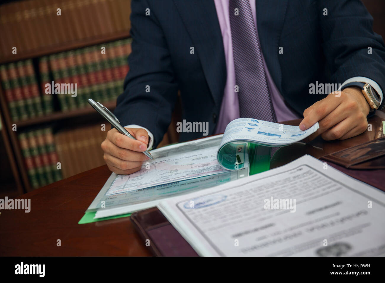 Close up of lawyer businessman sitting at table and signing document Stock Photo