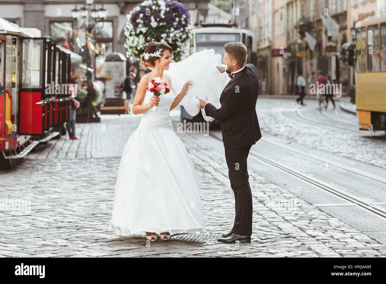 Bride and bridegroom walking across the street Stock Photo - Alamy