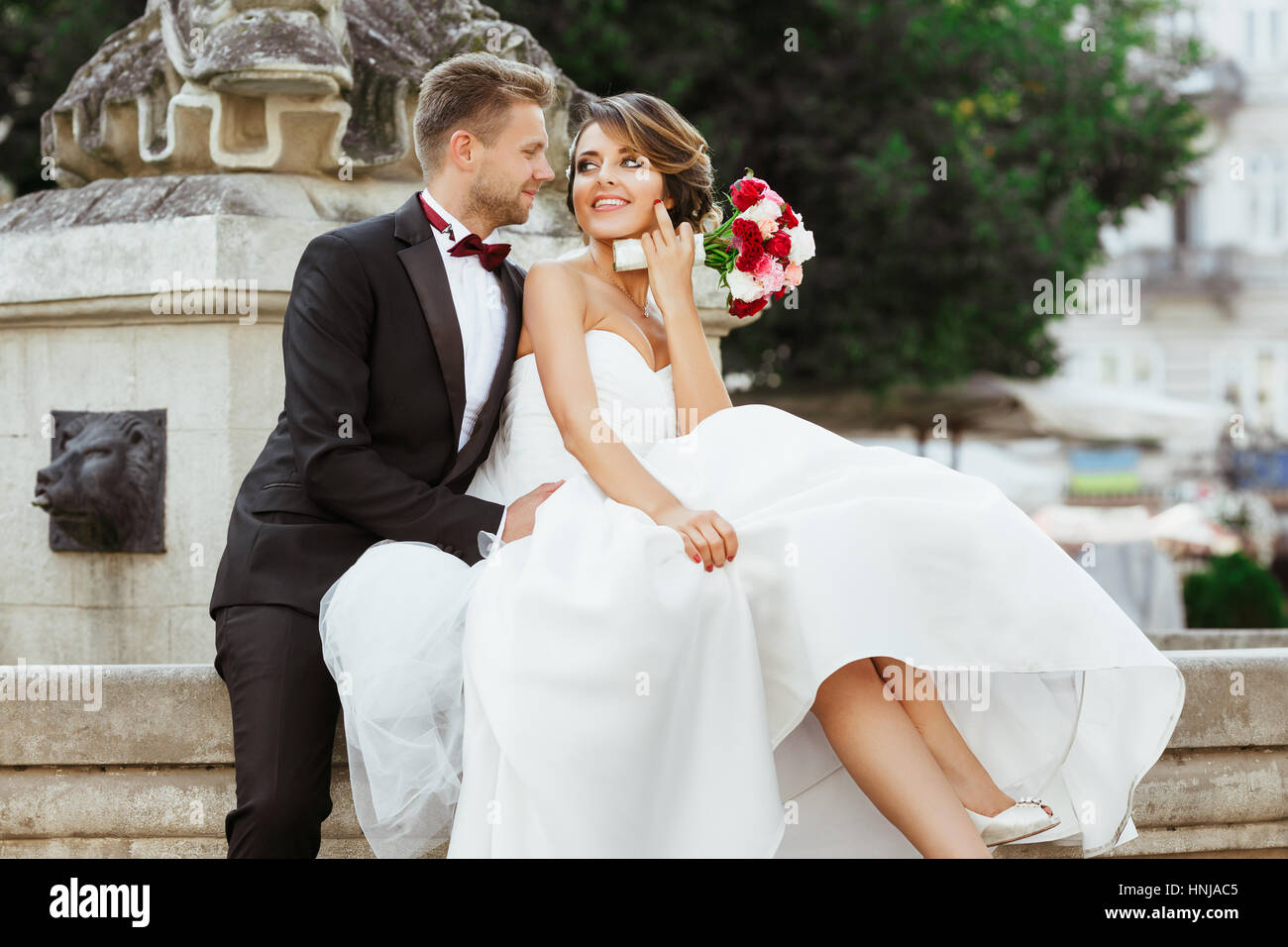 Bride and groom sitting near monument Stock Photo - Alamy