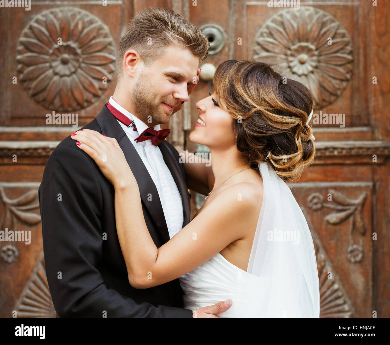 Groom and bride embracing near wooden door Stock Photo - Alamy