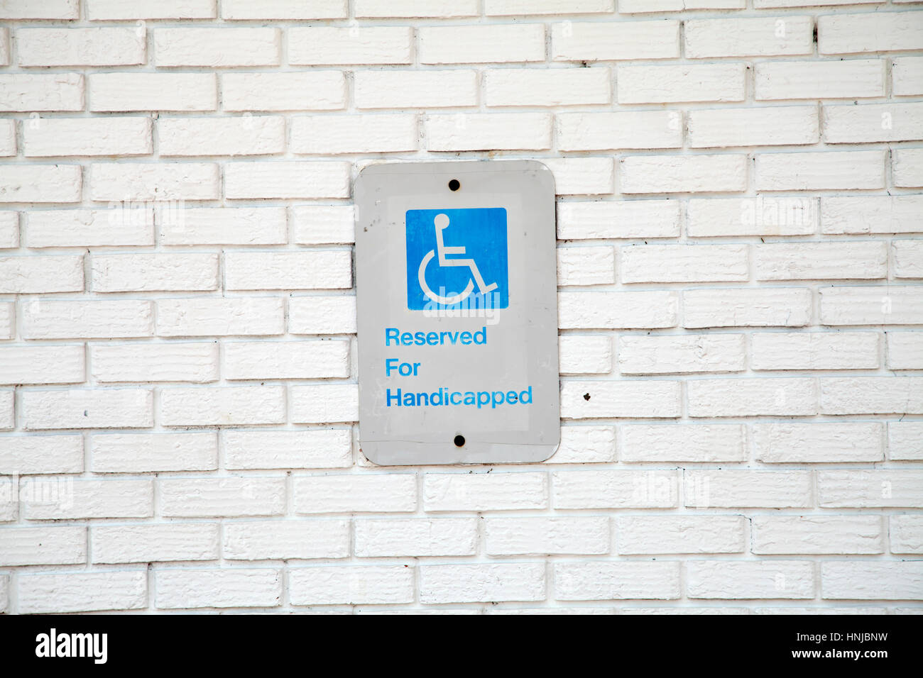 Handicapped parking sign on white brick background Stock Photo - Alamy