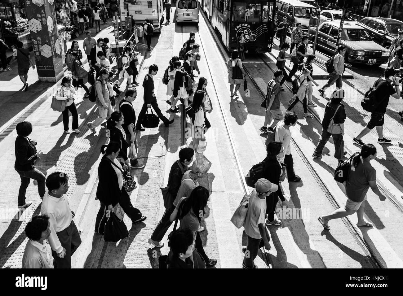 Hong Kong, Hong Kong - April 17 2015: People cross a street in Hong Kong island central district. Captured in black and white with a strong contrast. Stock Photo