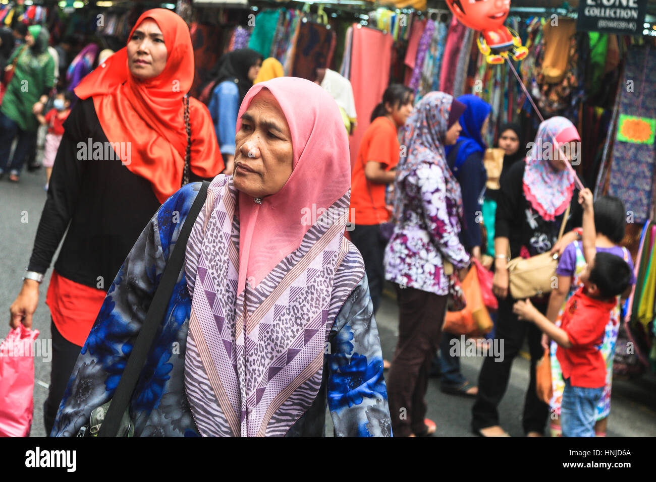 KUALA LUMPUR, MALAYSIA - MARCH 8, 2014: A woman wearing the traditional islamic headscarf walks in a shopping street in Little India district of Malay Stock Photo