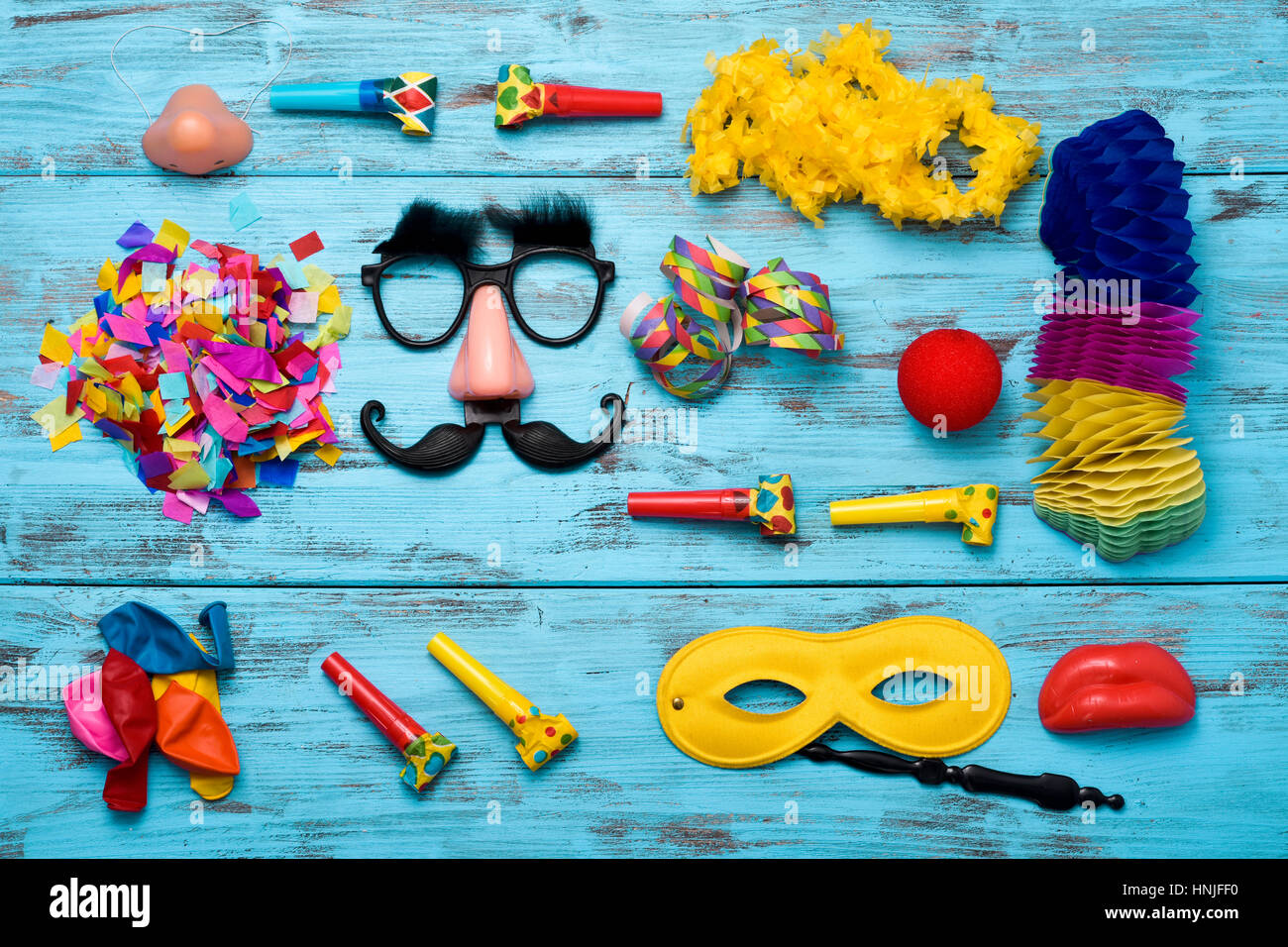 high-angle shot of different fancy dress party items on a blue wooden surface, such as a pair of fake black glasses with nose and mustache, a clown no Stock Photo