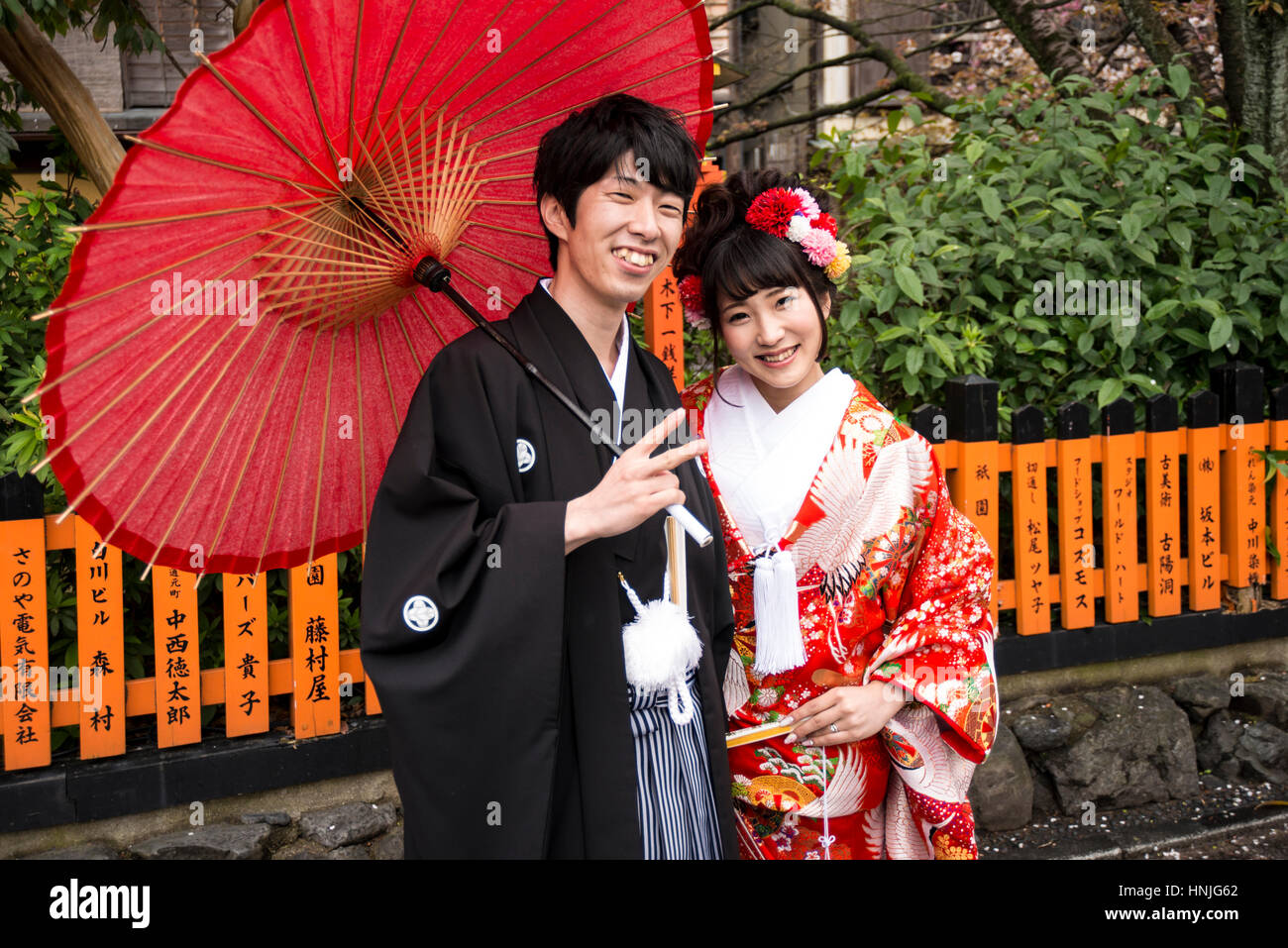 Newly weded young couple in traditional Japanese wedding attire posing for camera, Kyoto, Japan Stock Photo