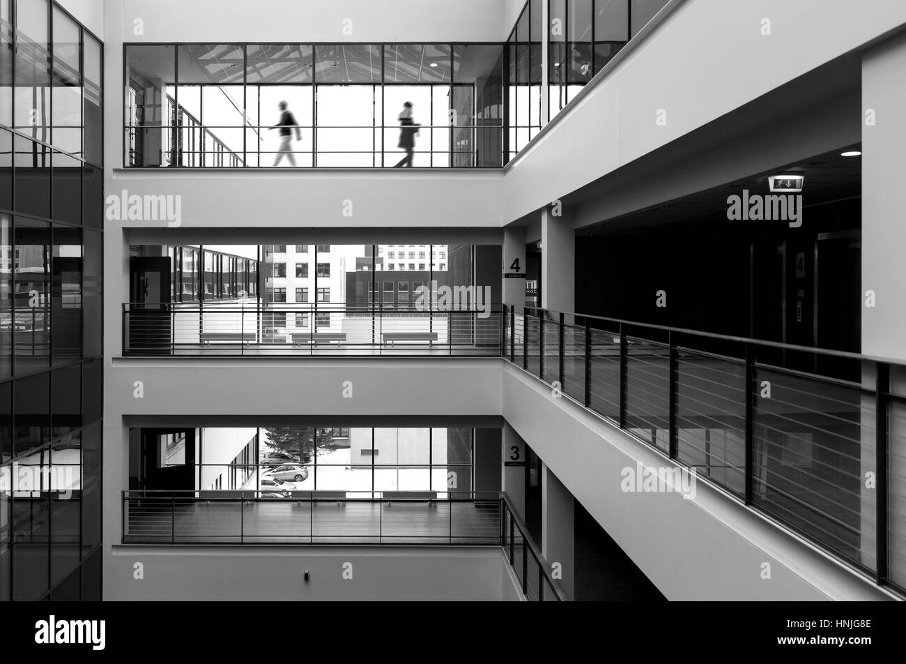 Modern public building interior with two figures walking in the background. High contrast black and white picture Stock Photo