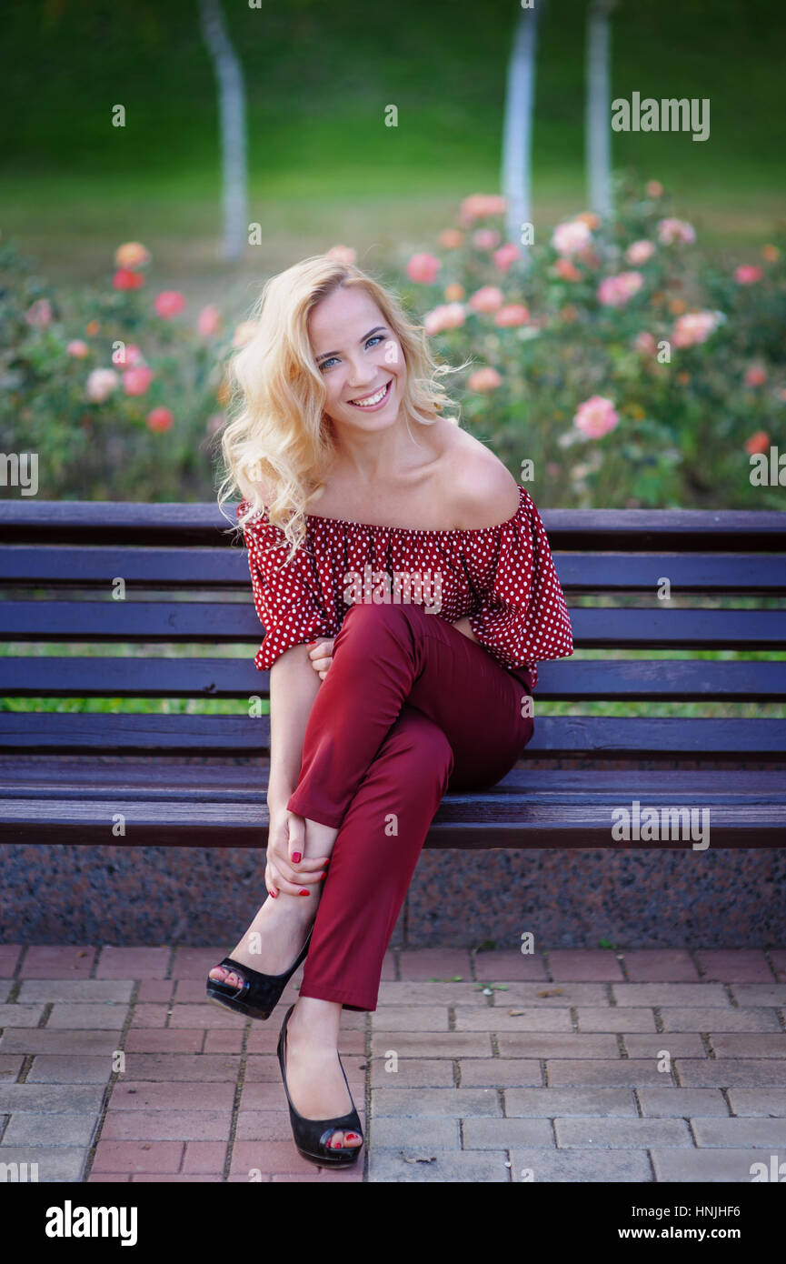 beautiful blonde woman sitting on a bench in the park Stock Photo - Alamy