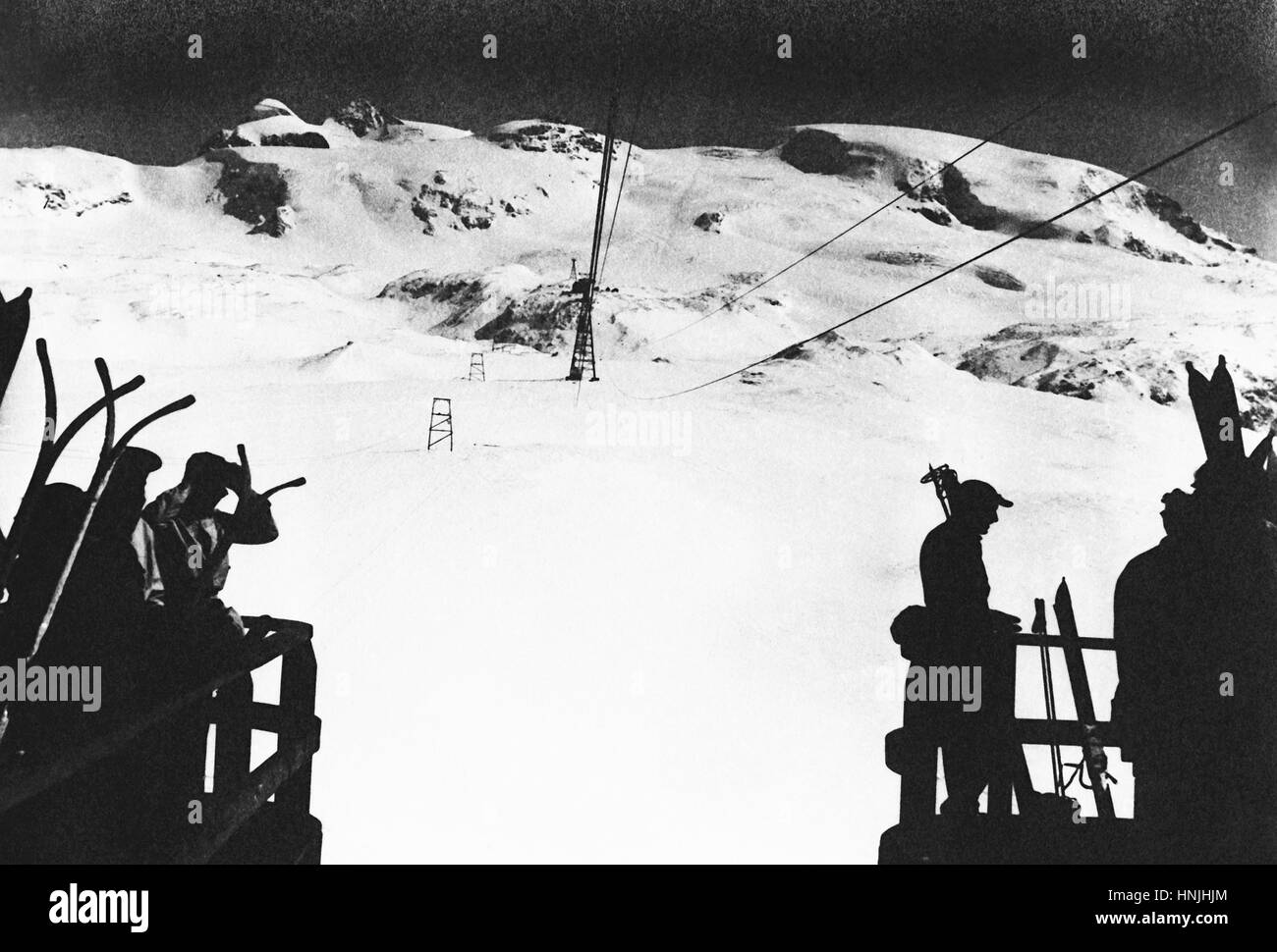 Dolomites,Italy 1939 - Backlight with skier silhouettes, waiting for the teleferic on Dolomites mountains, Italy. Scan from analog photography, private family collection before WWII. Stock Photo