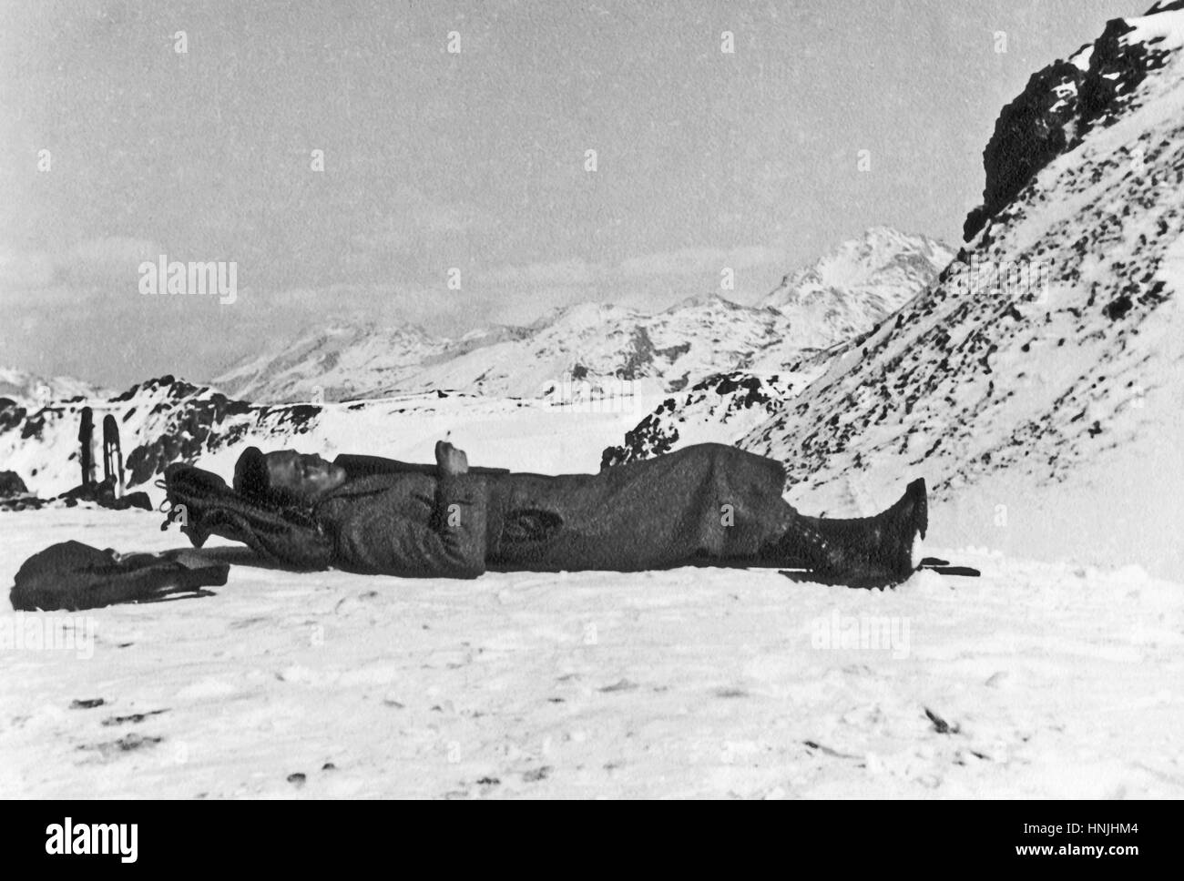 Pass Sorel, Italy 1939. Young tanned excursionist rests with a cigarette in hand laying down on the snow of a glacier of Italian Alps. Scan from analog photography, private family collection before WWII. Stock Photo