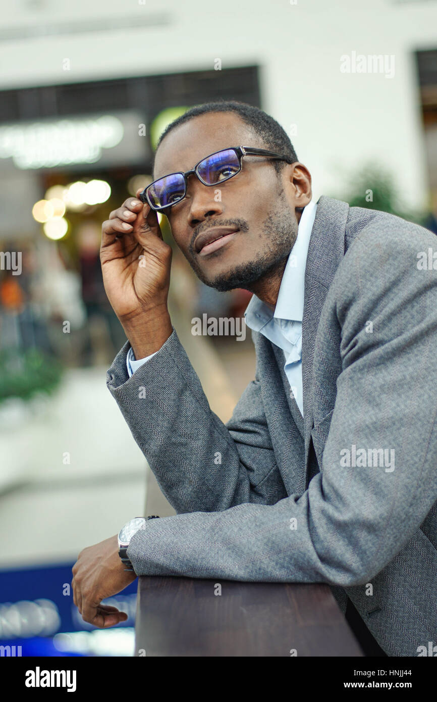 Portrait of handsome young afro american man leaning on the handrails ...