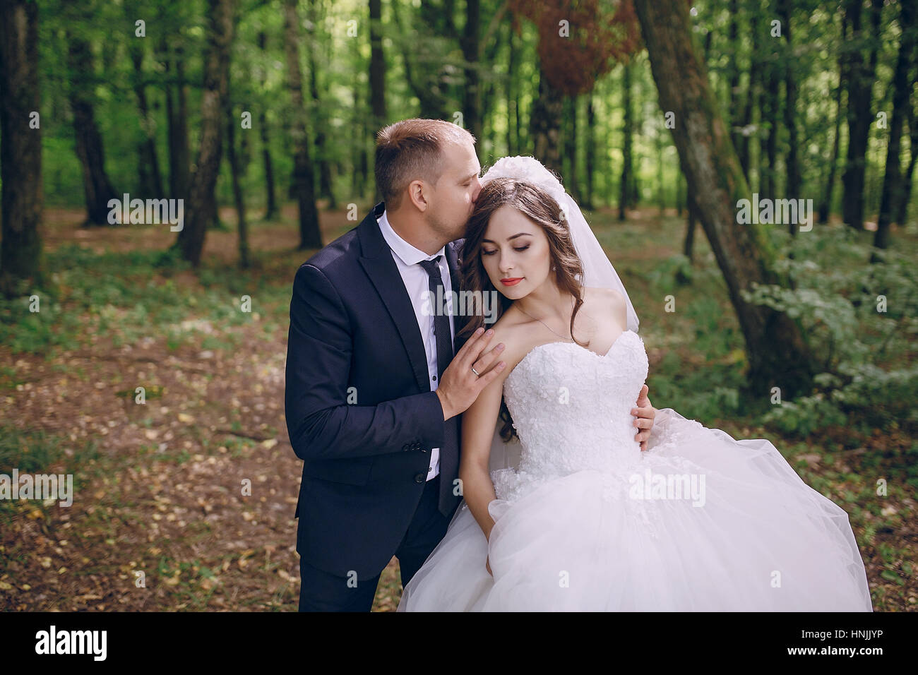 bride and groom walking in a green forest Stock Photo - Alamy
