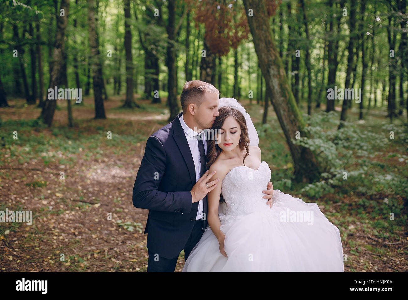 bride and groom walking in a green forest Stock Photo - Alamy