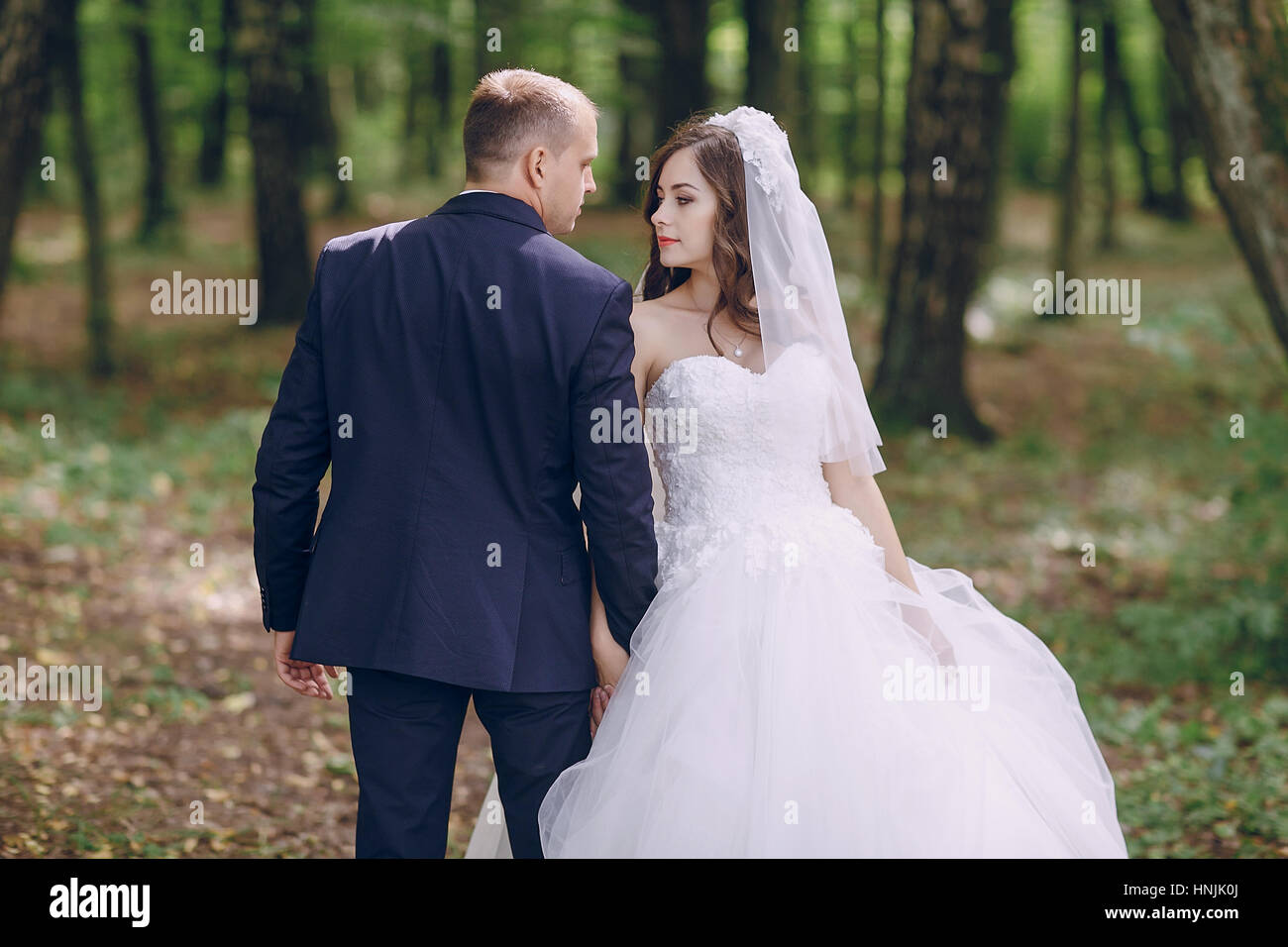 bride and groom walking in a green forest Stock Photo - Alamy
