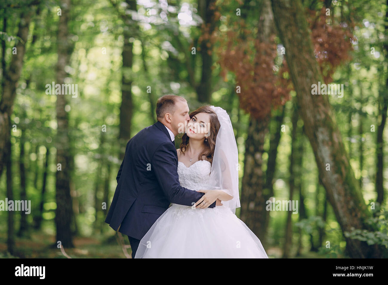 bride and groom walking in a green forest Stock Photo - Alamy