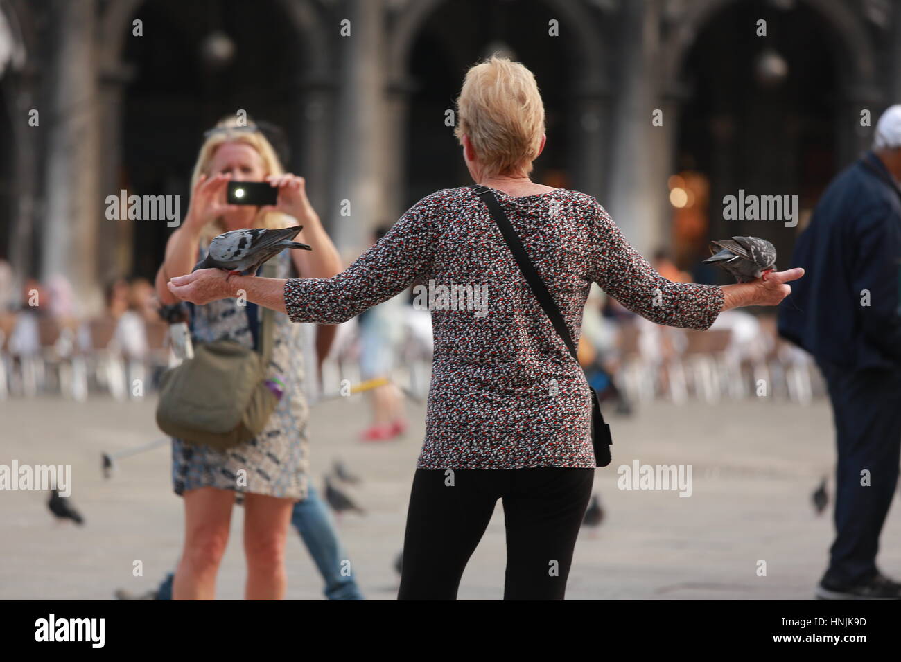 Tourists visit San Marco square in Venice.They take pictures and selfie and enjoy with the pigeons. Stock Photo